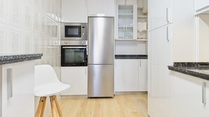 A modern kitchen with white cabinets, a stainless steel refrigerator, a microwave, and an oven. - Apartment 'Osiris' with Wi-Fi (San Andrés del Rabanedo)
