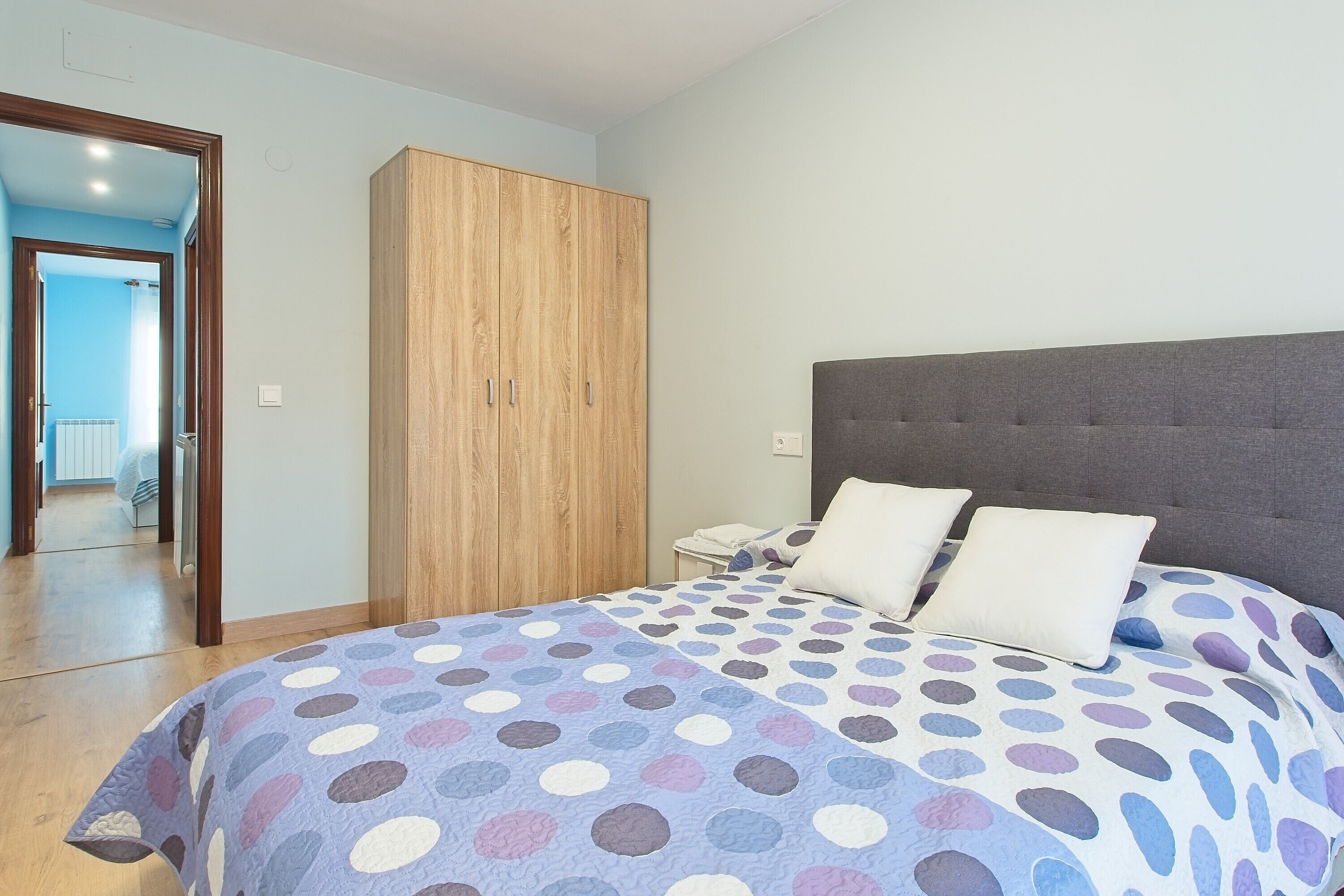A bedroom with a bed, a wardrobe, and a nightstand.