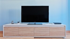 A modern entertainment unit with a flat-screen TV, a sound system, and a charging station. - Apartment 'Osiris' with Wi-Fi (San Andrés del Rabanedo)