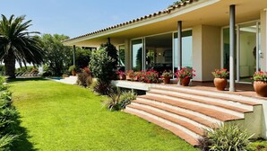 Ein modernes Haus mit überdachter Veranda, Schwimmbad und gepflegtem Garten.