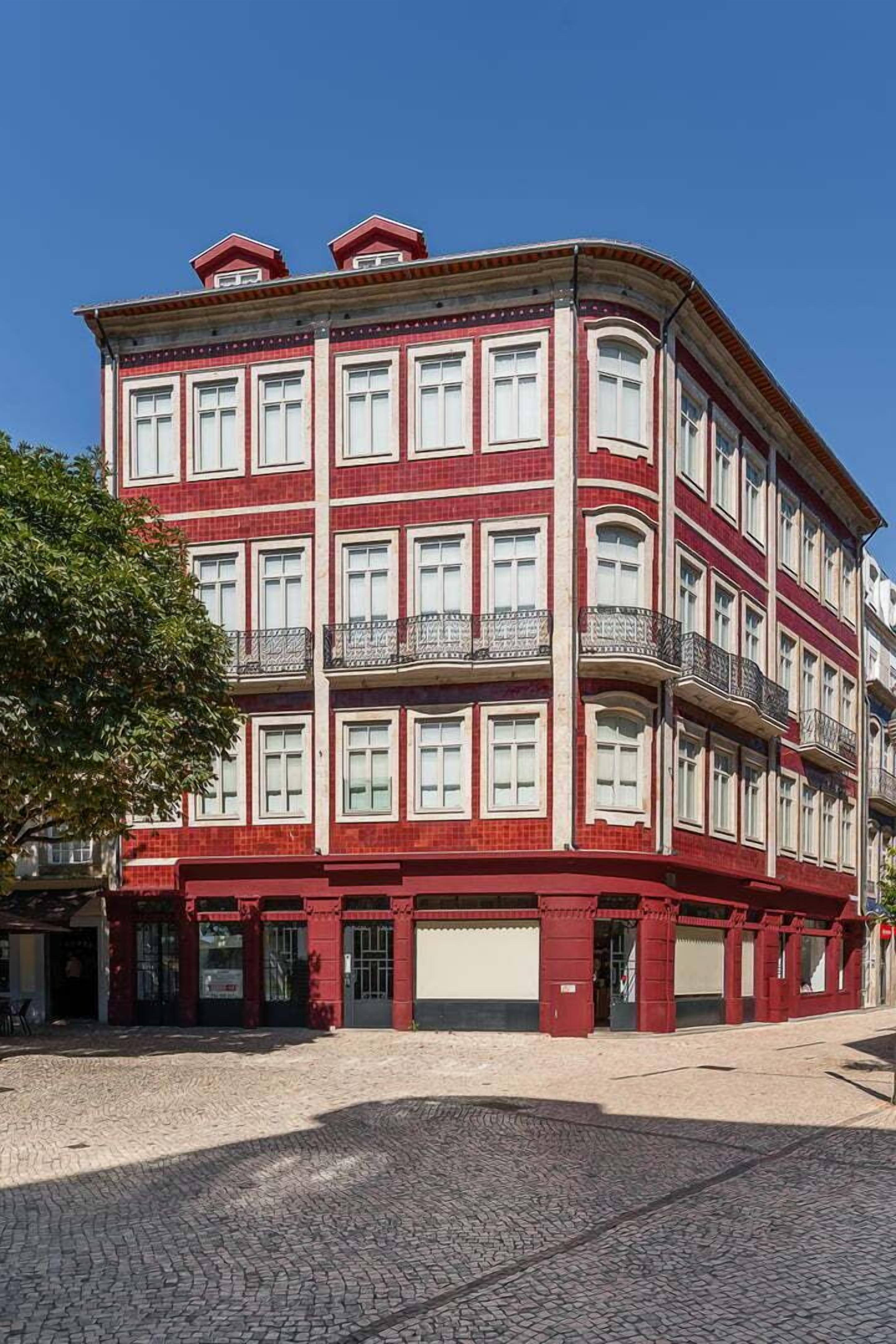A red and white building with multiple floors, balconies, and a cobblestone ground.
