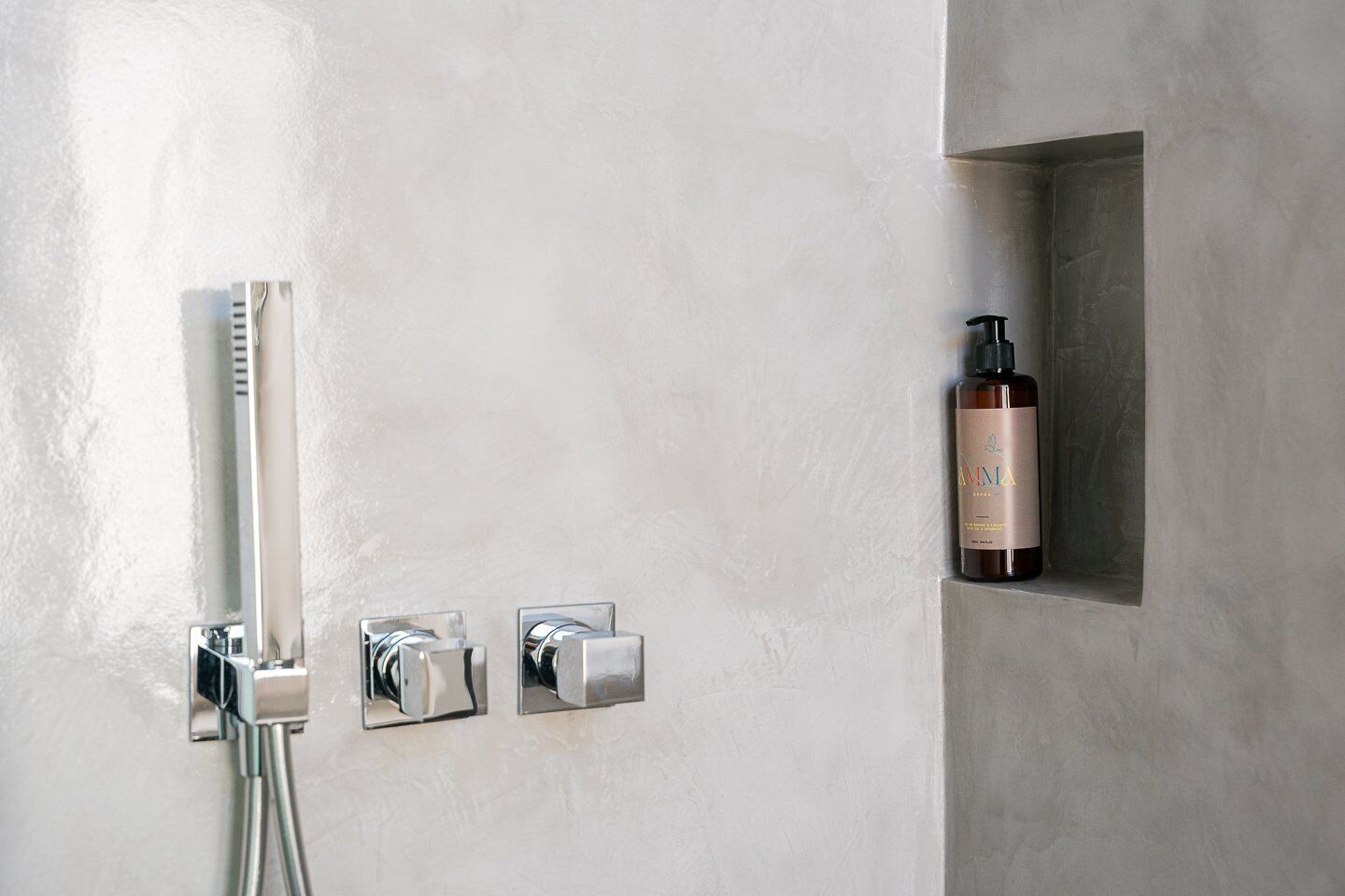 A modern bathroom with a shower, a bottle of shampoo, and a towel rack.