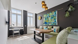 A modern living room with a sofa, a dining table, and a large window. - GuestReady - AMMA Braga - 8 (Braga)