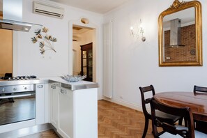 A kitchen with a stove, oven, and white cabinetry. There is a dining table with chairs and a mirror on the wall.