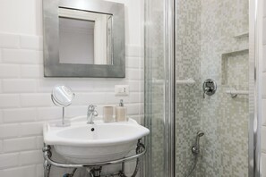 A bathroom with a white sink, mirror, and two soap dispensers.