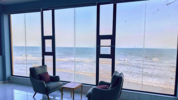 Una habitación con ventanas amplias vistas al océano, dos sillones y una pequeña mesa.