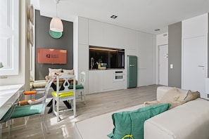 Een modern appartement met een eethoek, kitchenette en een woonkamer met een bank en een televisie.