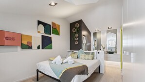 A modern bedroom with a bed, artwork, and a bathroom with a mirror and sink. - GuestReady - AMMA Braga - 9 (Braga)
