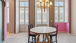 A dining area with a round wooden table, black chairs, and a chandelier. - GuestReady - AMMA Braga - 7 (Braga)