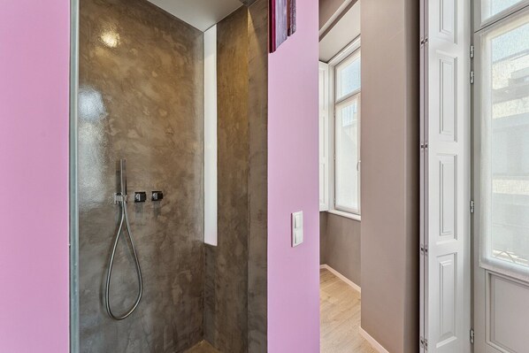 A bathroom with a shower, a door, and a window.