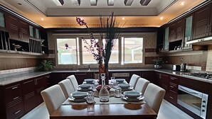 A modern kitchen with dark wooden cabinets, a central island, and a dining area with a large table set for six.
