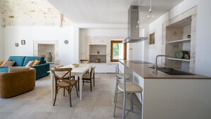 A modern kitchen with a central island, a dining area with a table and chairs, and a living area with a sofa and a coffee table. - Palmento Giorgio: historic countryside retreat in the Itria Valley (Martina Franca)