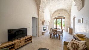 A spacious living area with a television, dining table, and a cozy seating area. - Palmento Giorgio: historic countryside retreat in the Itria Valley (Martina Franca)