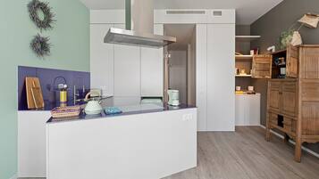 Una cocina moderna con una isla central, armarios blancos y un mueble de madera con espacio de almacenamiento.