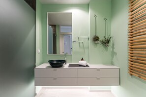Un baño con un espejo grande, un lavabo negro, una toalla y un revestimiento de pared de listones de madera.