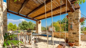 A rustic outdoor seating area with a stone wall, wooden furniture, and hanging planters. - Villa Nina Large Private Pool, A/C, WiFi (Scicli)