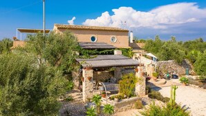 A traditional Mediterranean villa with stone walls, a tiled roof, and a garden with various plants and a cactus. - Villa Nina Large Private Pool, A/C, WiFi (Scicli)
