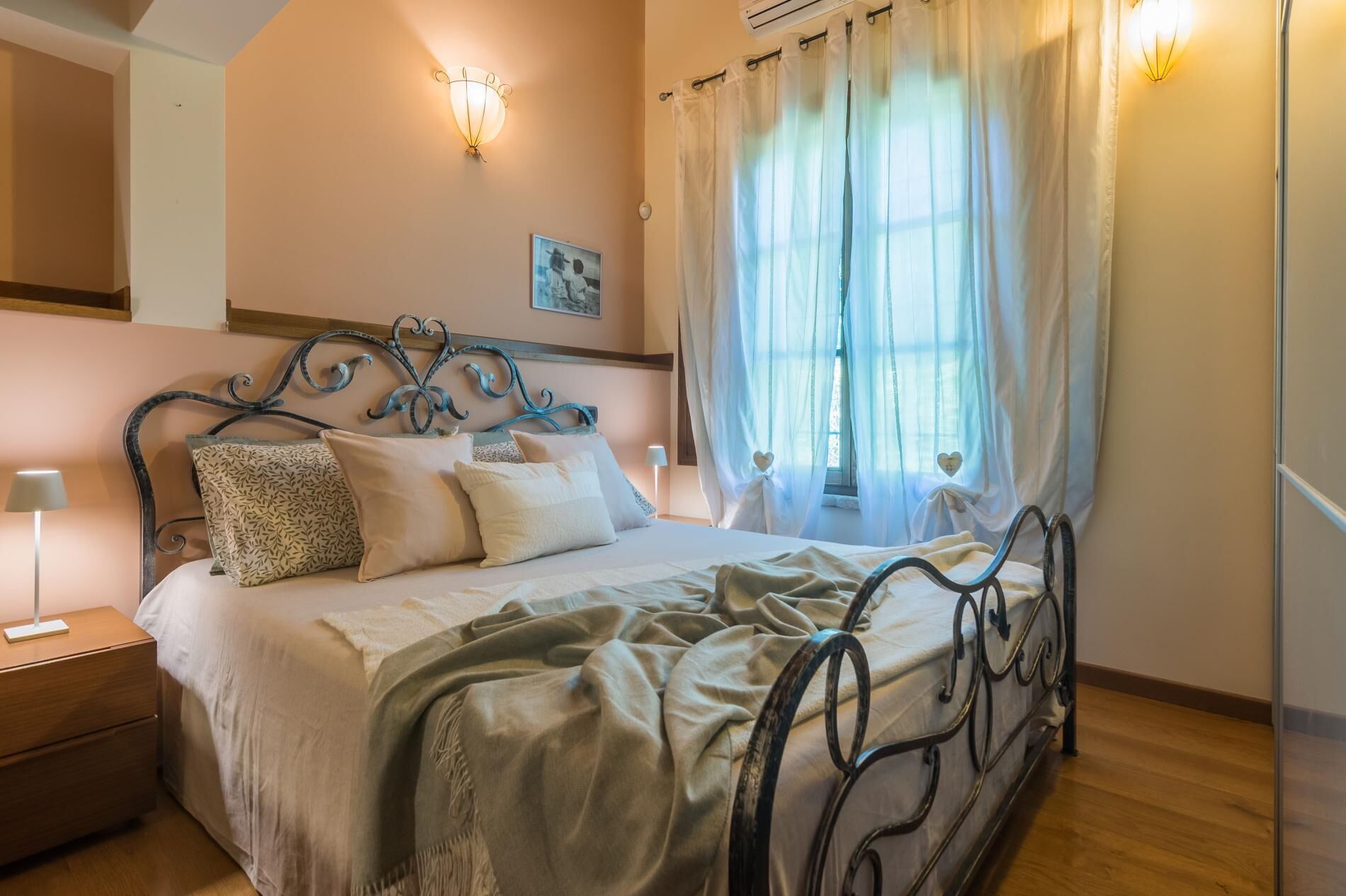 A bedroom with a bed, bedside table, lamp, and a window with curtains.