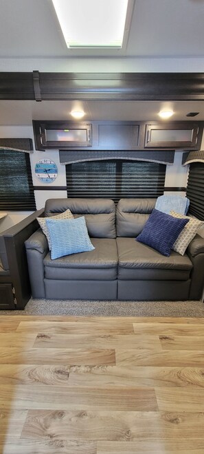 A modern living area with a sofa, a clock, and a ceiling light.
