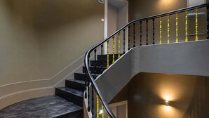 Un escalier en colimaçon moderne, avec des marches en bois foncé et des rampes noires agrémentées de touches de jaune.