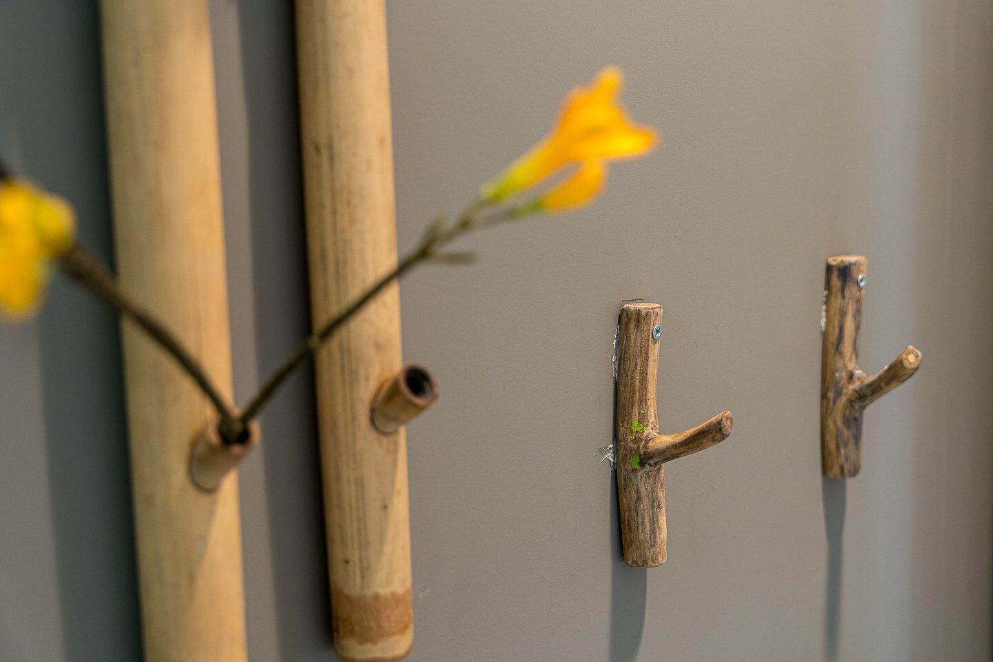 Una pared con tres palos de madera y dos ganchos de madera.