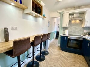 Eine Küche mit Barbereich, Holzboden und modernen Geräten.