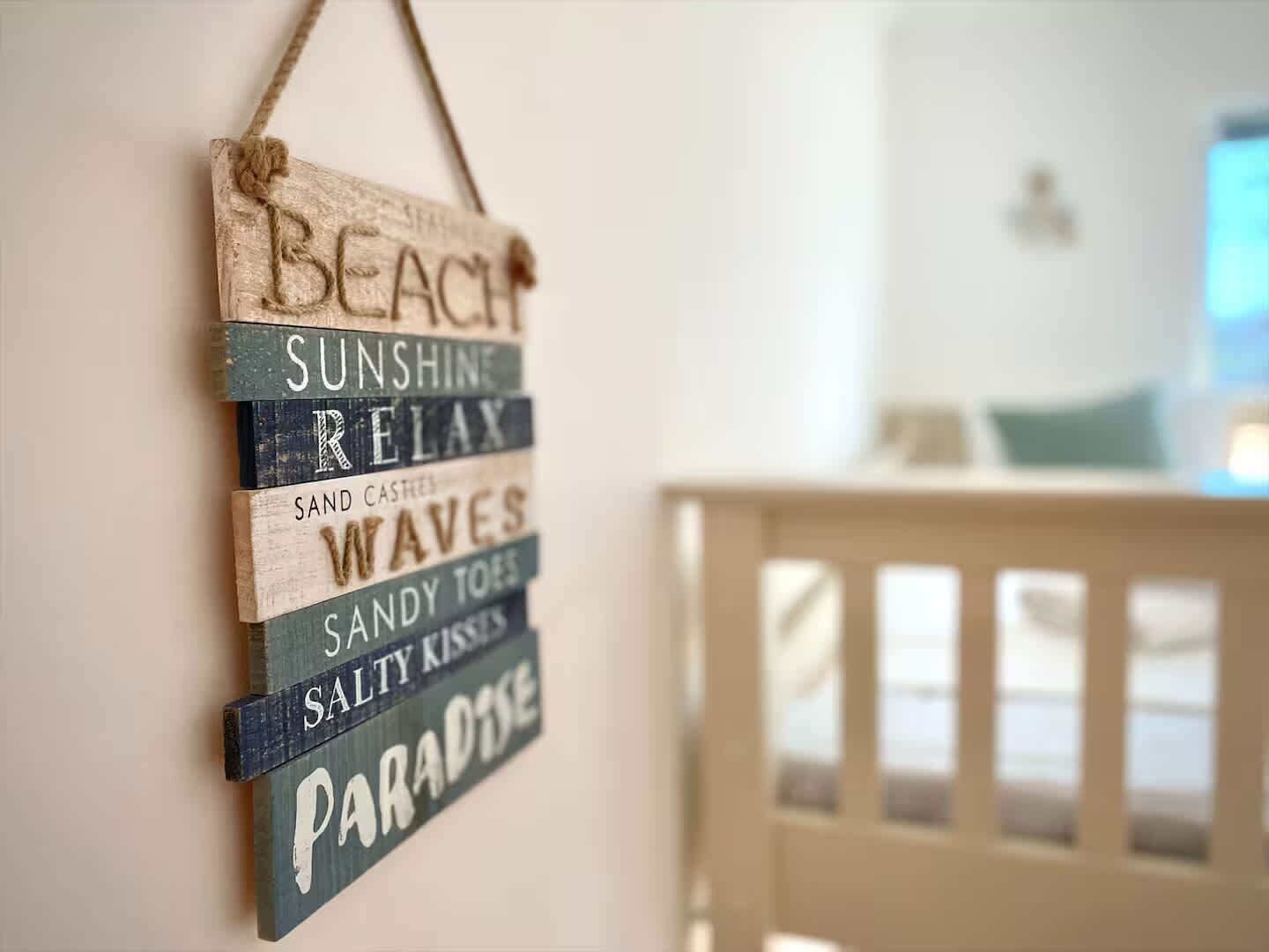 A wooden sign with words like "BEACH," "SUNSHINE," and "RELAX" hanging on a wall.