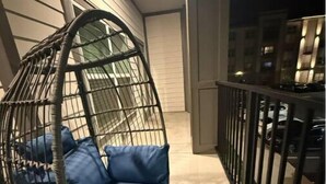 A hanging chair with blue cushions on an outdoor balcony. - Luxurious Plush Apartment (McDonough)