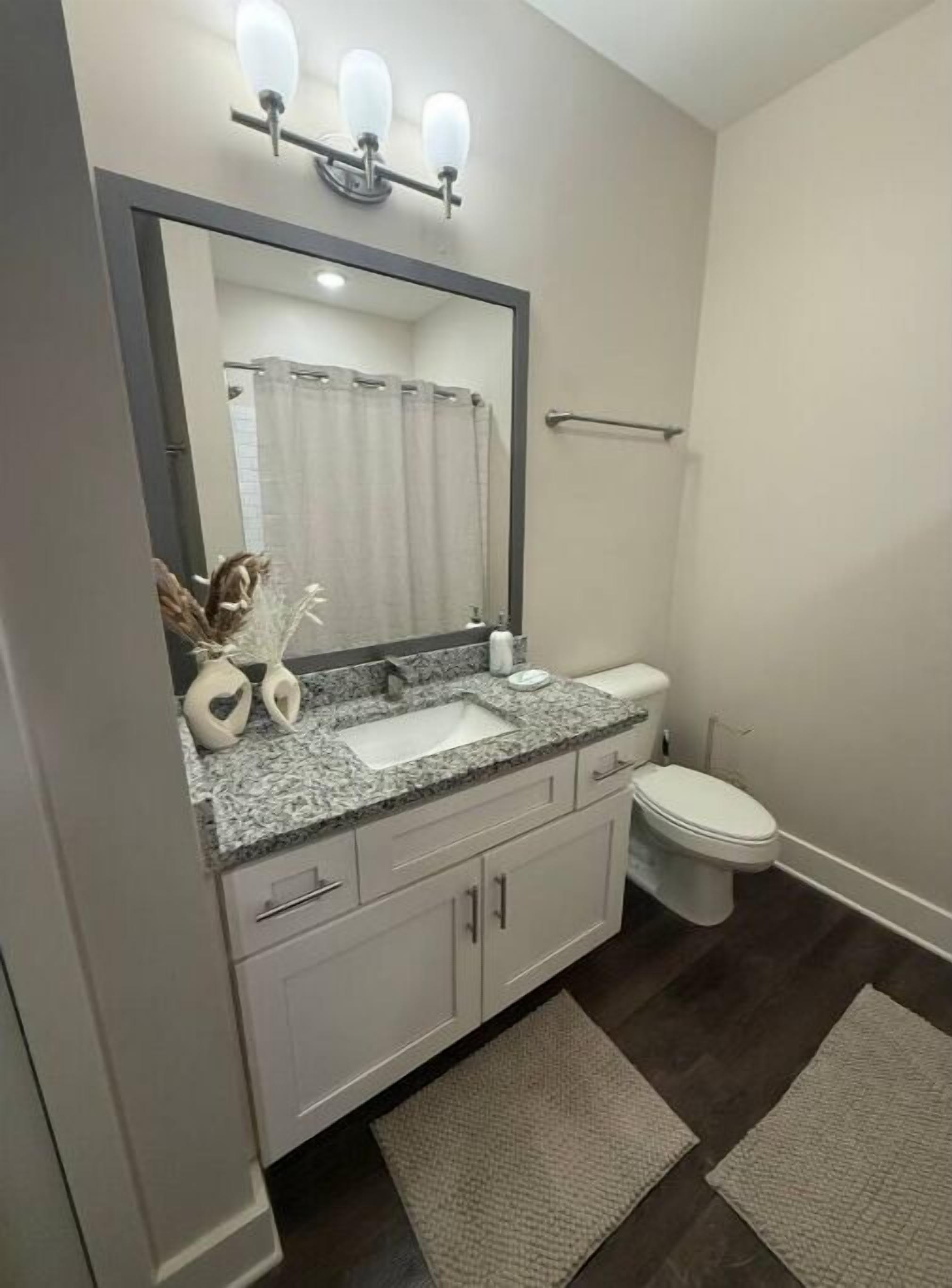 A bathroom with a vanity, sink, mirror, and toilet.