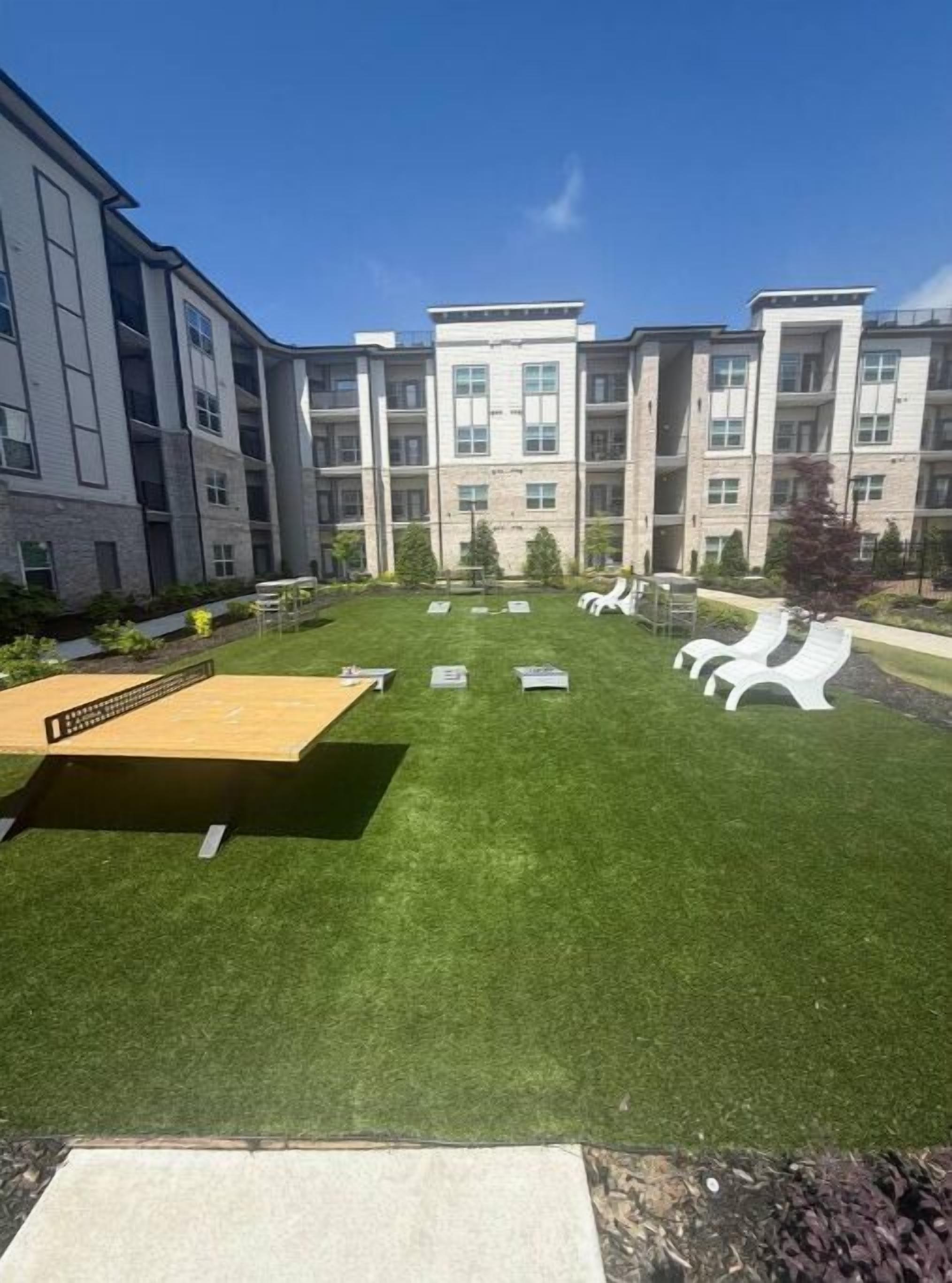 Un patio con cubierta de madera, sillas reclinables blancas y una pequeña zona de piscina.