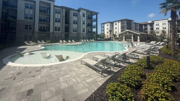 A modern hotel with a pool area, lounge chairs, and a landscaped garden. - Luxurious Plush Apartment (McDonough)