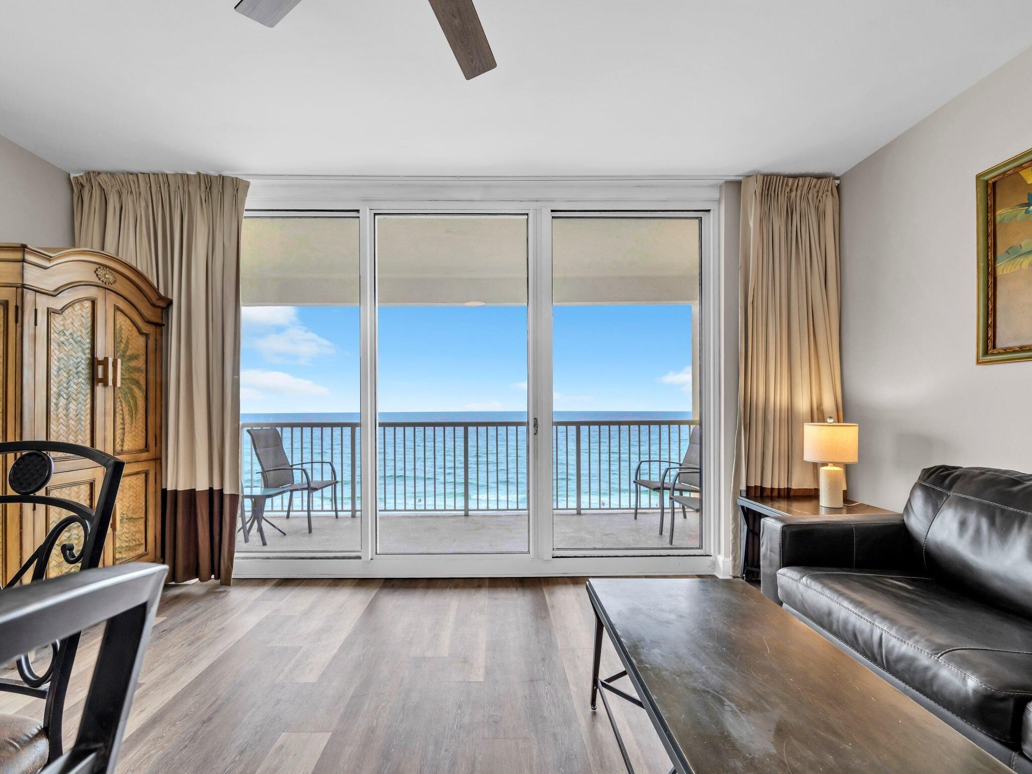 Une chambre d’hôtel avec un balcon, un canapé, une table à manger et un buffet.