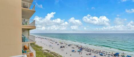 A beach view from an apartment balcony with a clear sky and ocean.