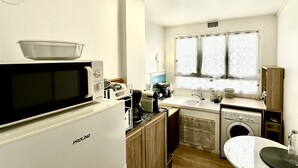 A compact kitchen with a microwave, coffee maker, and a washing machine. - Studio with beautiful view of the Eiffel Tower, 10 minutes' walk from the Champs-de-Mars (Paris)