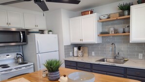 Een moderne keuken met witte kastjes, een roestvrijstalen koelkast, een magnetron, een fornuis en een spoelbak.