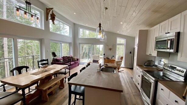 A spacious kitchen with a dining area, large windows, and a view of the outdoors.