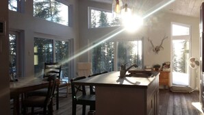 A modern kitchen with a central island, large windows, and a deer skull decoration.