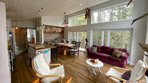 A spacious living area with a wooden floor, a dining table, and a red sofa.