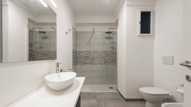 Une salle de bain moderne avec un lavabo blanc, des toilettes et un espace douche.