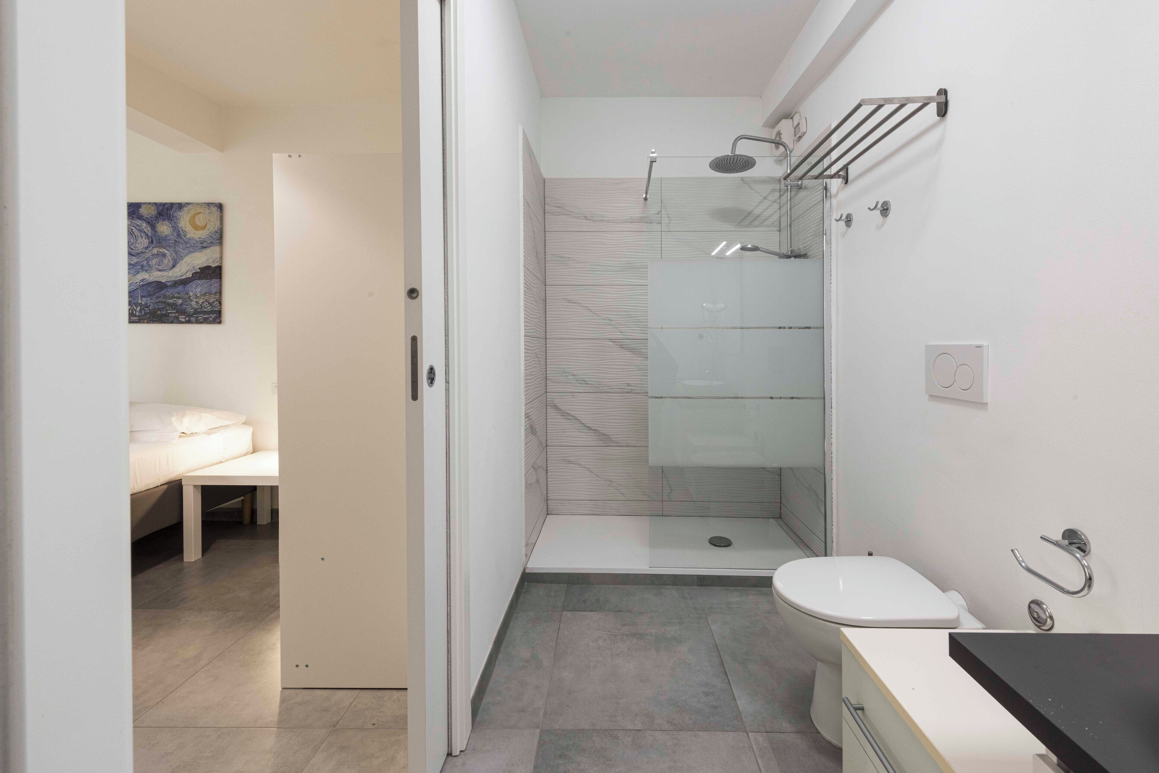 A modern bathroom with a glass shower enclosure, a toilet, and a sink.