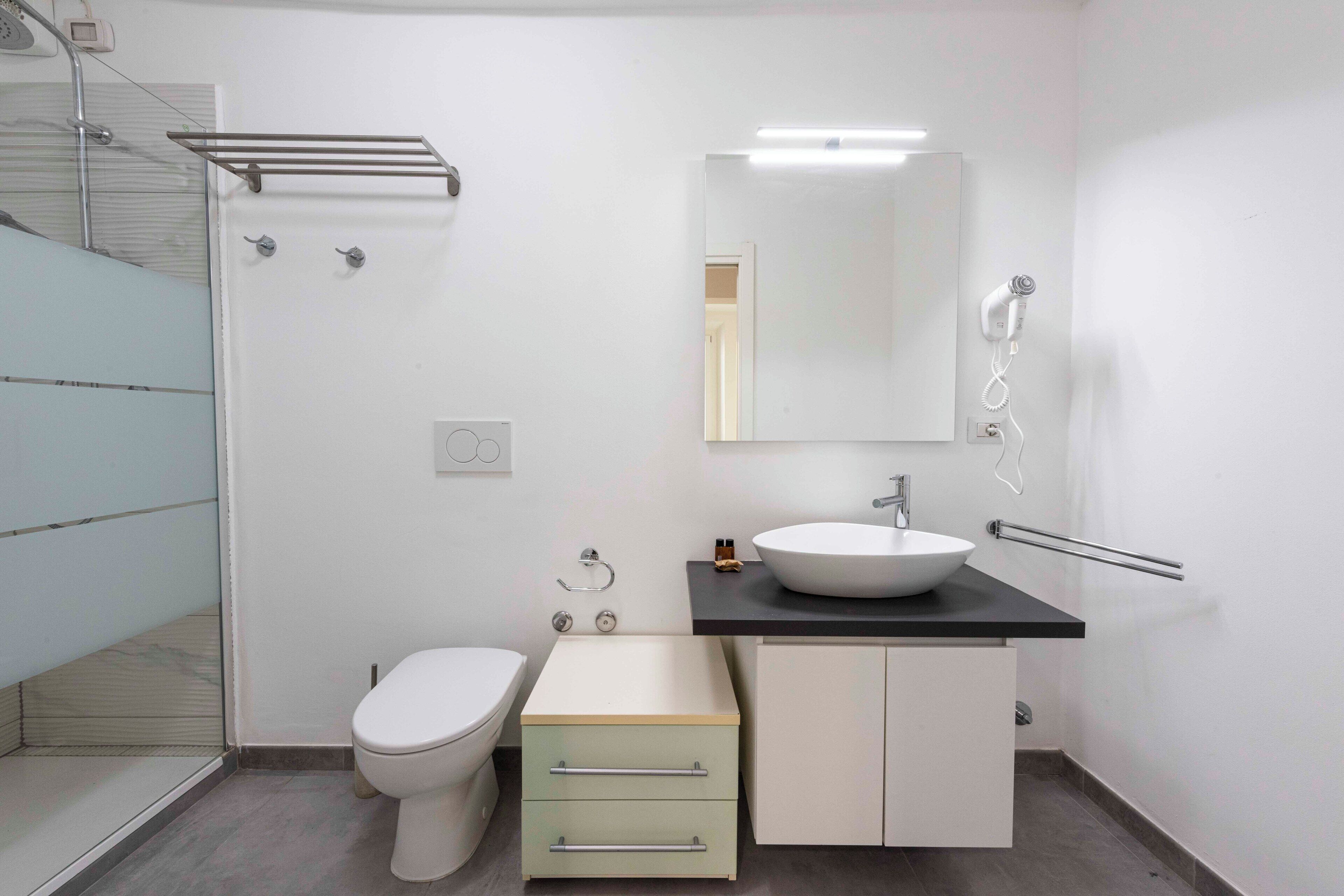 A modern bathroom with a toilet, sink, and shower.