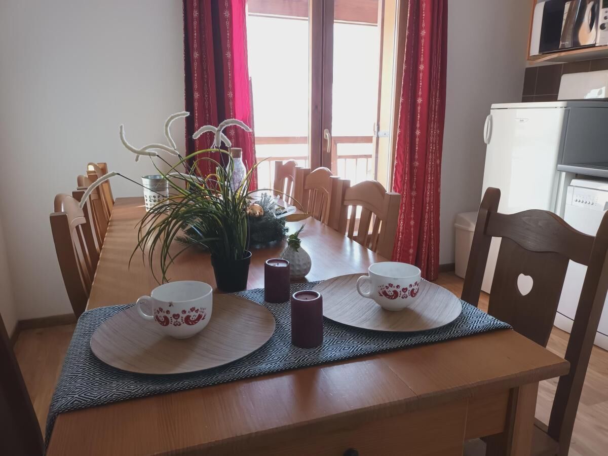 Una mesa de comedor dispuesta con dos tazas blancas, una planta en maceta y velas.