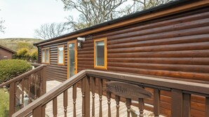 A log cabin with a wooden deck and a staircase leading to the entrance.