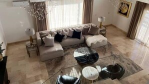 Un salón amplio con un sofá grande, una mesa de centro de cristal y una araña.