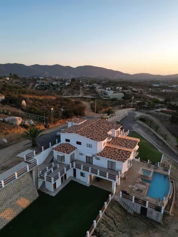 A residential area with a white building featuring a tiled roof and a swimming pool.