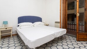 Een slaapkamer met een bed, een nachtkastje, een lamp en een houten deur.