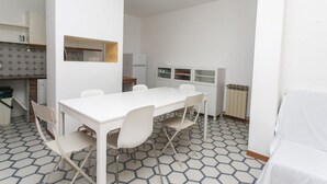 Een moderne keuken met witte kasten, een witte eettafel met vier stoelen, en een vloer met een honingraatpatroon.
