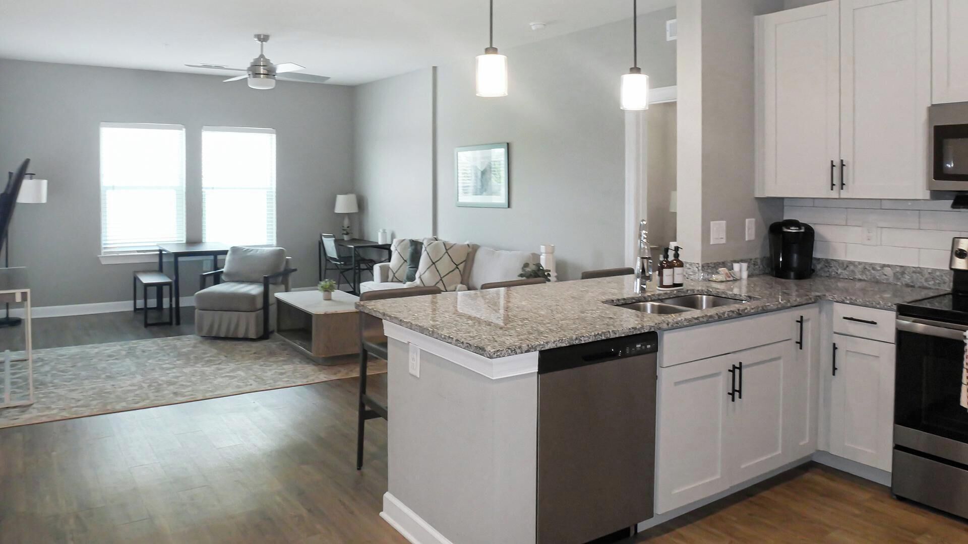 A modern kitchen with granite countertops, stainless steel appliances, and white cabinetry.