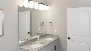 A bathroom with two sinks, a large mirror, and a towel ring.