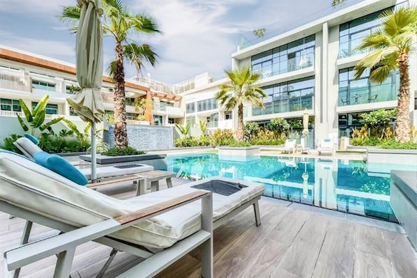 A pool area with lounge chairs and palm trees.